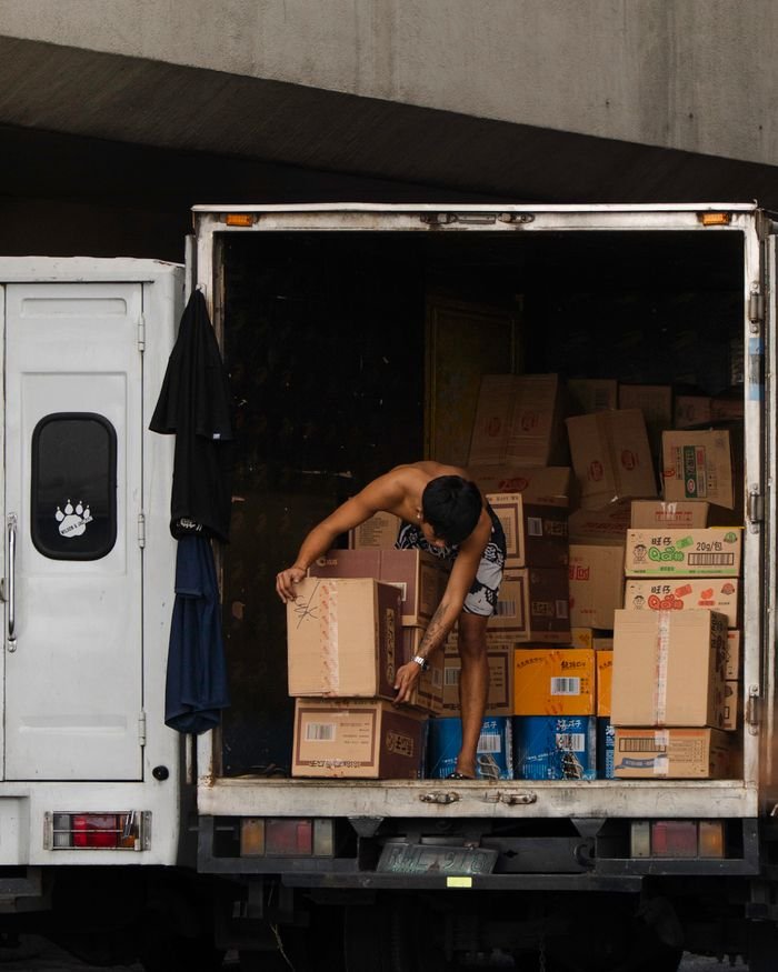 Delivery worker loads boxes onto a truck, illustrating shipping and logistics.